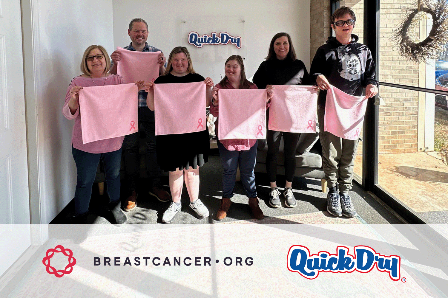 A group of Quick Dry employees holding pink towels