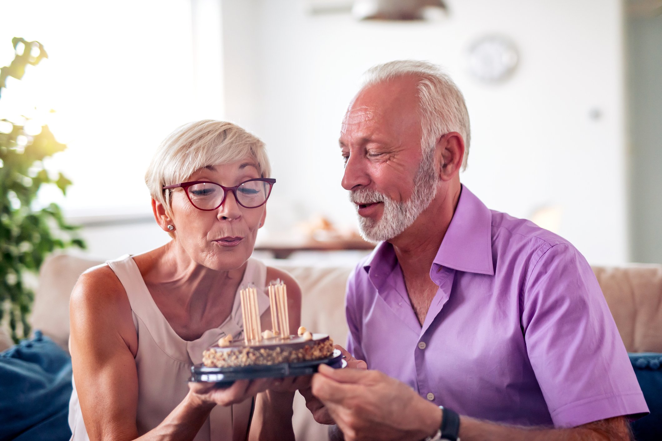 Two people blowing out candles on a cake
