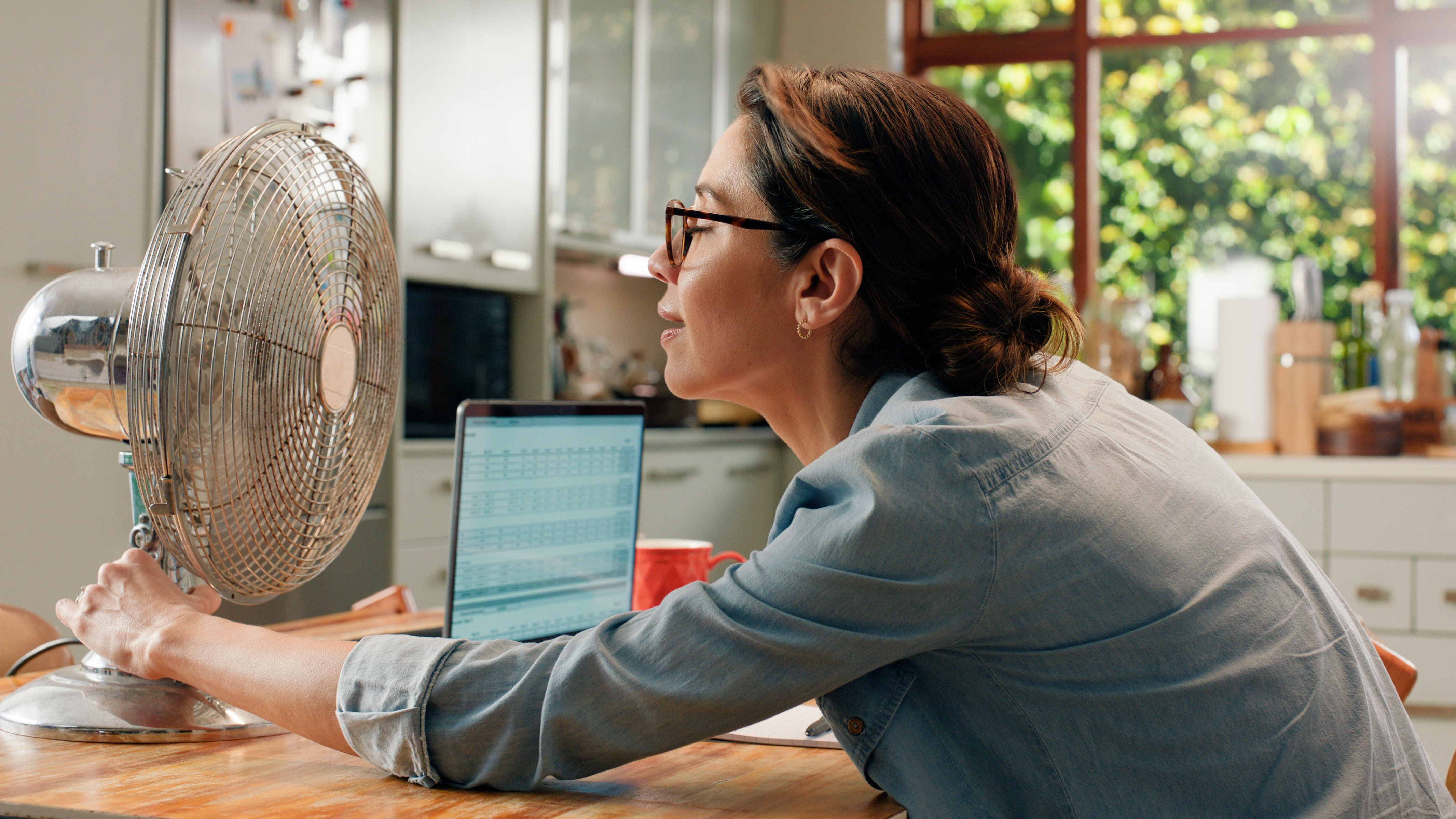 A woman cooling herself in front of a fan